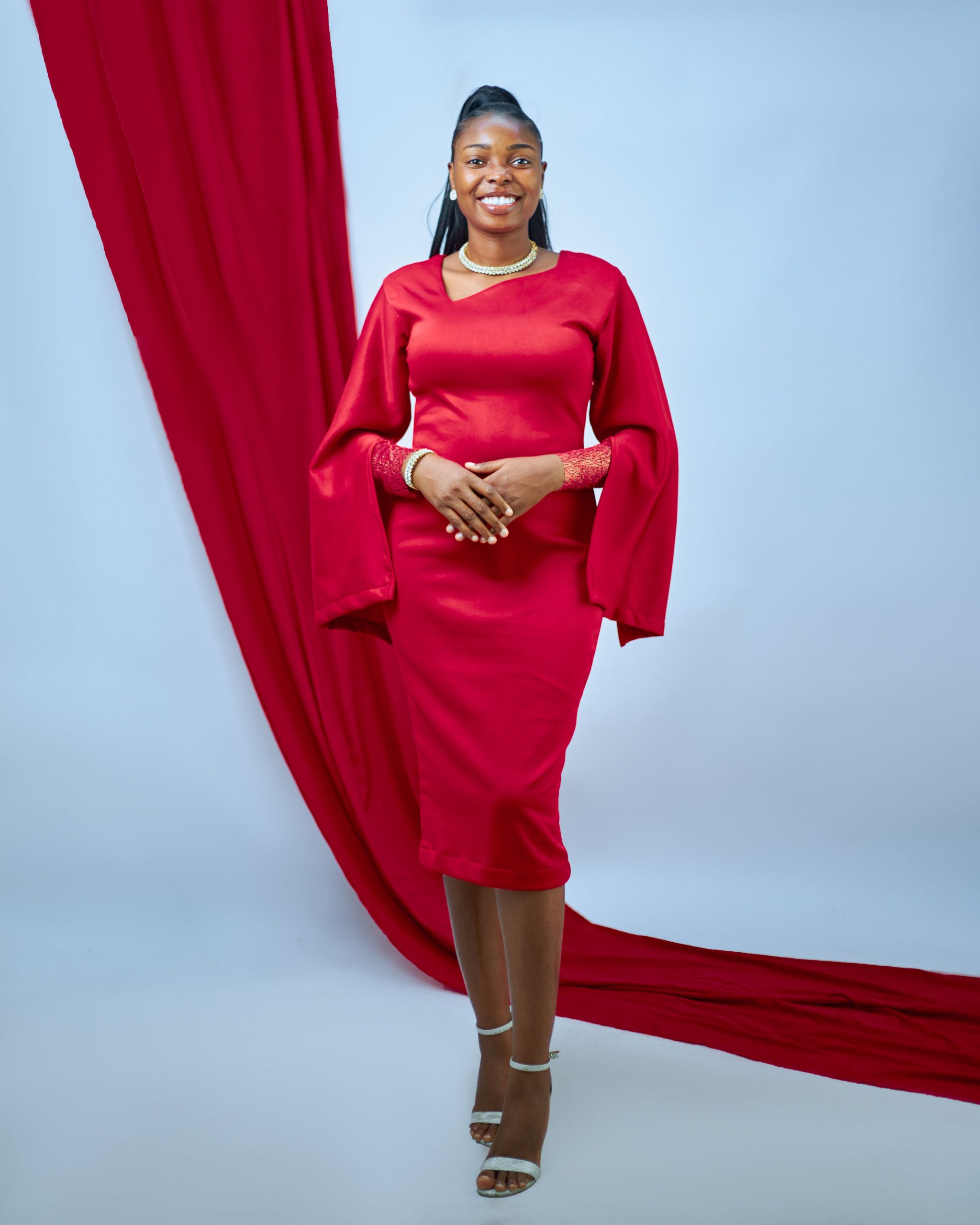 Model in a flowing red dress against a pale blue studio background